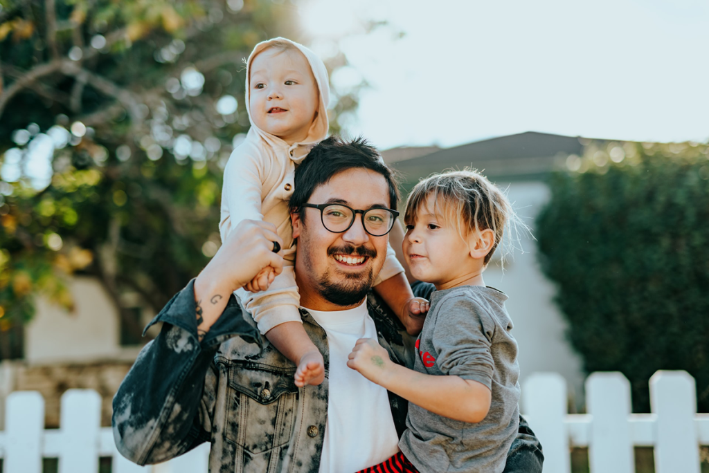 Moving with kids. Dad and his sons standing in front of house
